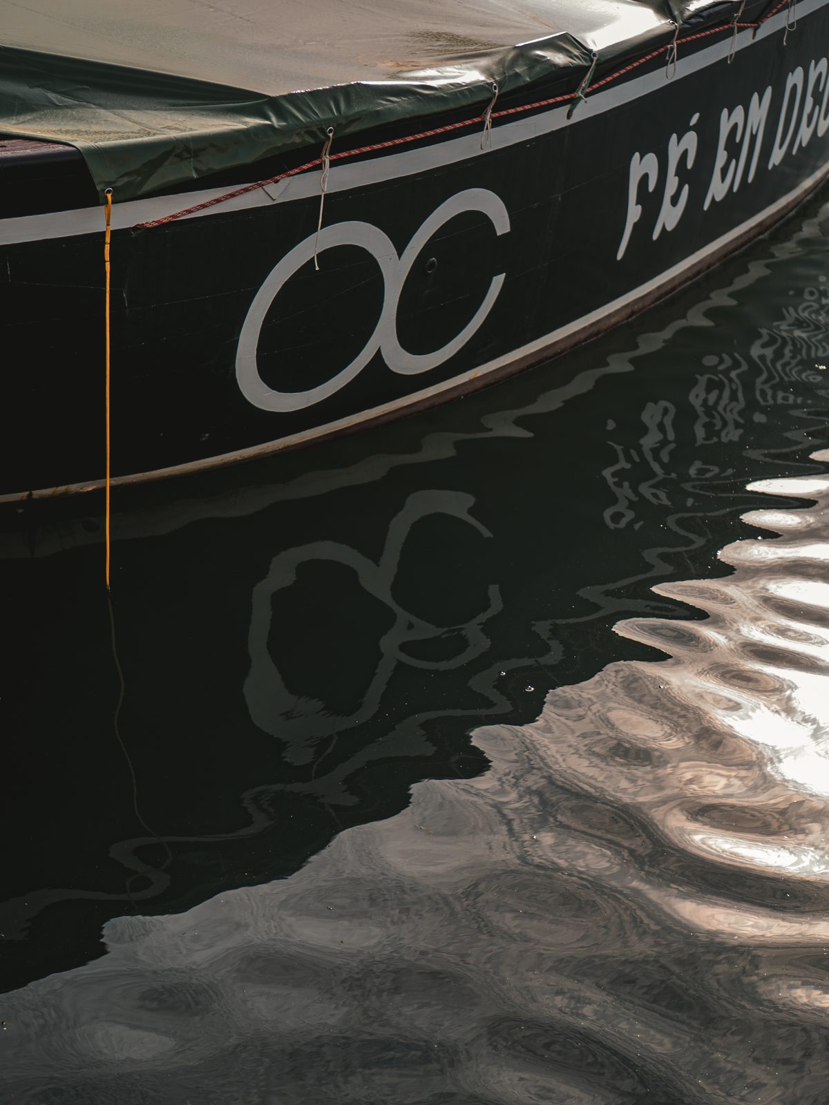 Sigla pintada no casco do barco refletida na água da marina
