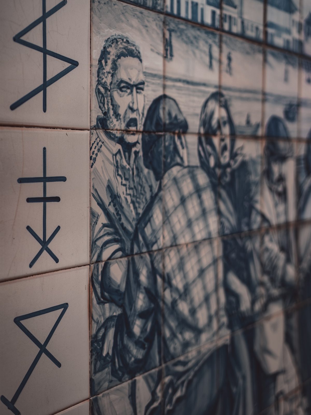 Detalhe de painel de azulejos com cena da comunidade piscatória e siglas na margem